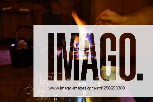 The waiter putting a burning sugarloaf over a bowl of Feuerzangenbowle on a restaurant table *** der Kellner putting einer brennend sugarloaf trueber einer Schüssel des Feuerzangenbowle am einer Gaststätte Tisch 6803780 RECORD DATE NOT STATED