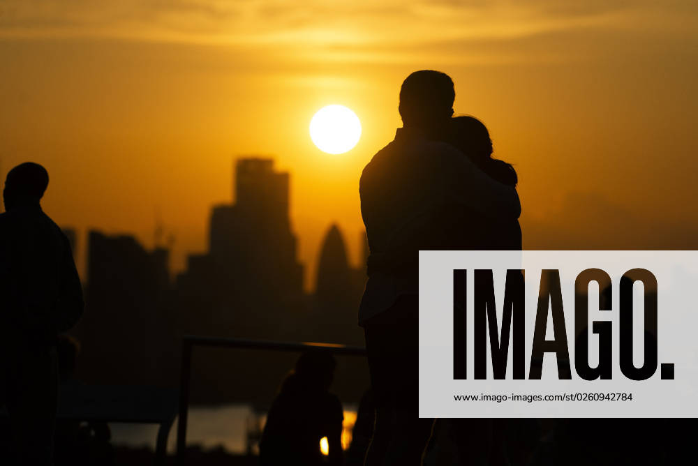 Two people hug as the watch the sunset over London on the Summer Solstice (21st June) seen from Greenwich Park, London. Greenwich London England Greenwich Park