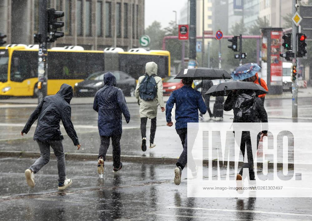 Rainy weather Berlin, 23 06 2023 People in rain gear run across a pedestrian walkway during heavy rainfall Strong thunderstorms have moved over parts of Germany Berlin Berlin Germany