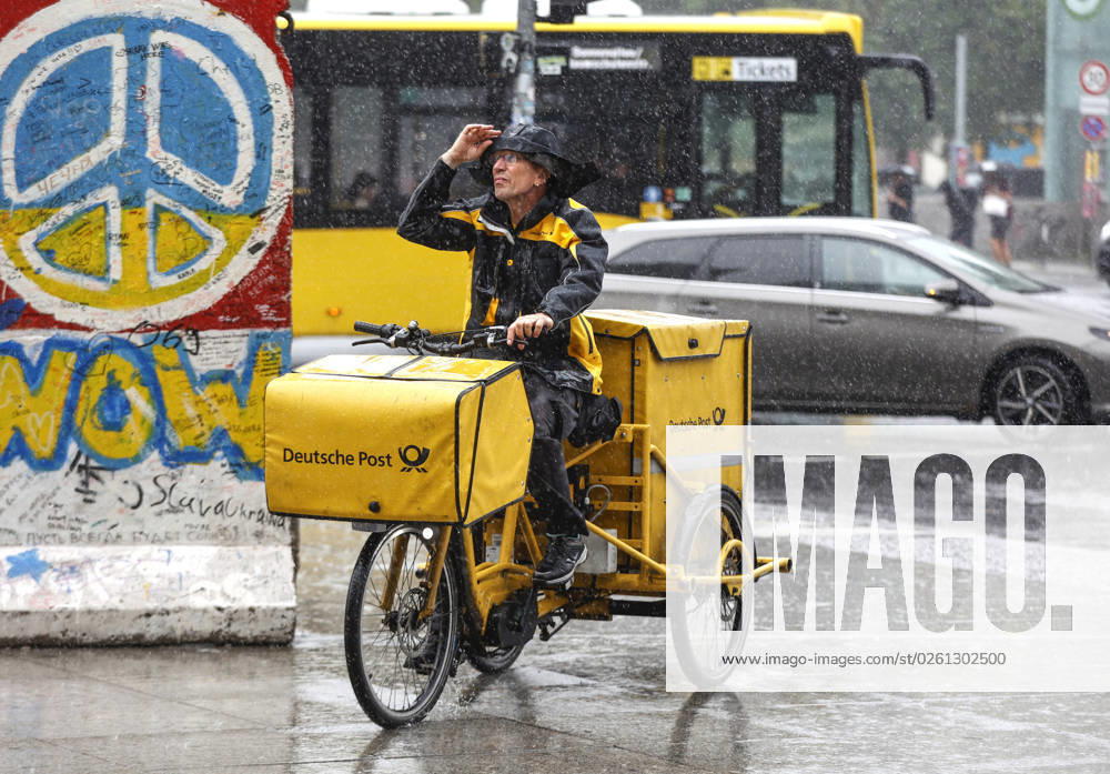 Rainy weather Berlin, 23 06 2023 A DHL mail carrier rides his e-bike over a sidewalk in heavy rain Heavy storms have moved over parts of Germany Berlin Berlin Germany