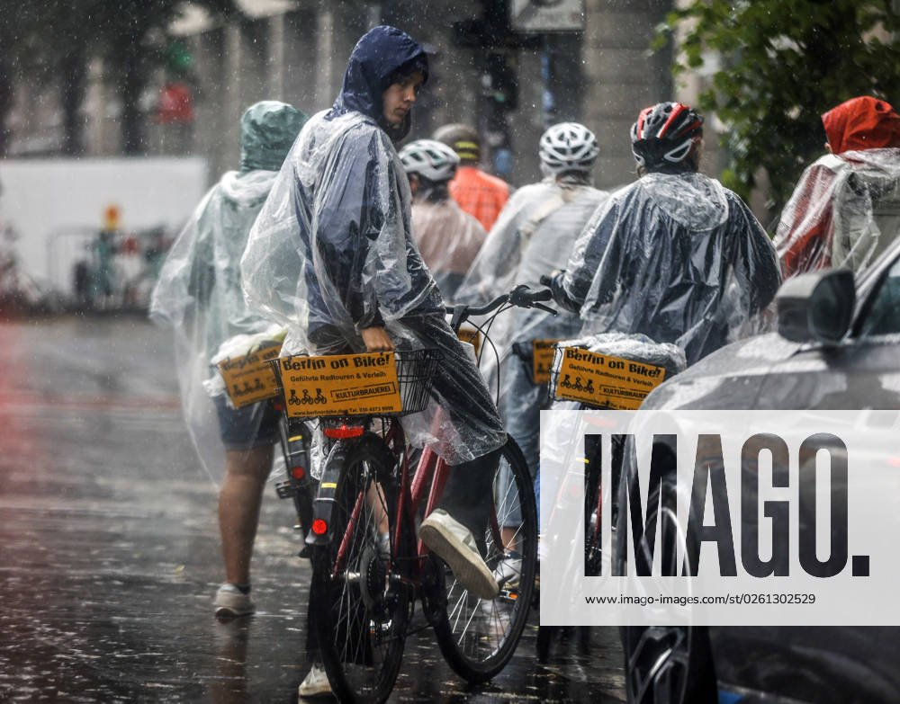 Rainy weather Berlin, 23 06 2023 Tourists of a Berlin On Bike bicycle tour protect themselves with rain capes from heavy rainfall Heavy thunderstorms have moved over parts of Germany Berlin Berlin Germany