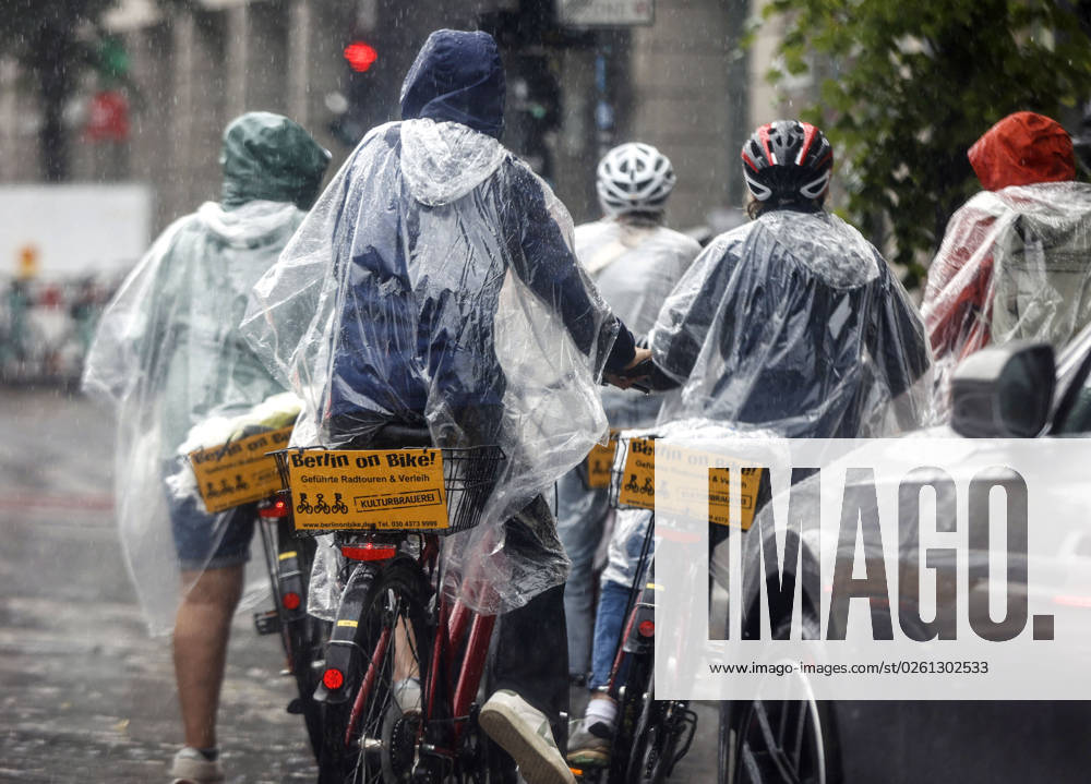 Rainy weather Berlin, 23 06 2023 Tourists of a Berlin On Bike bicycle tour protect themselves with rain capes from heavy rainfall Heavy thunderstorms have moved over parts of Germany Berlin Berlin Germany
