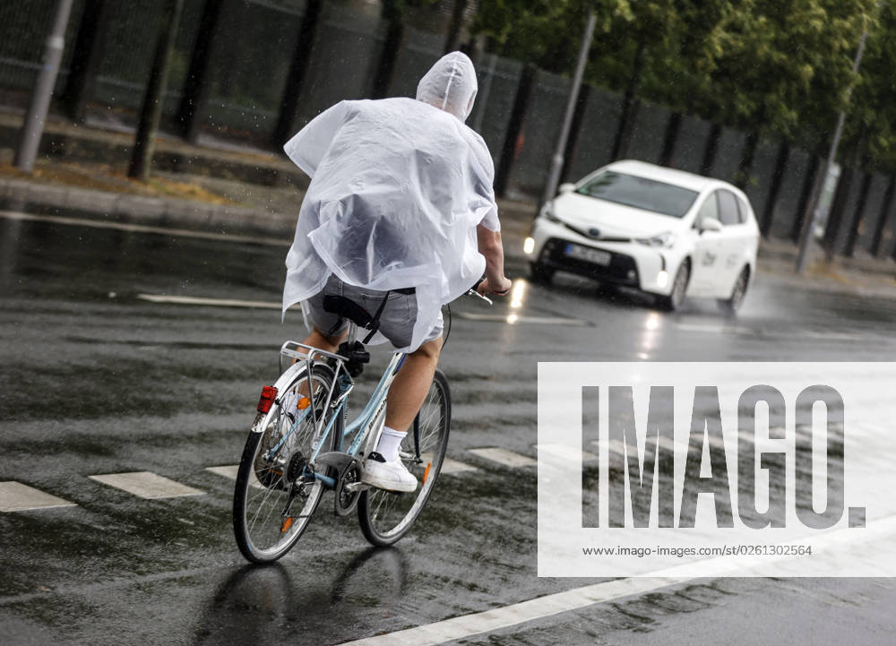 Rainy weather Berlin, 23 06 2023 A cyclist protects himself from heavy rainfall with a rain cape Strong thunderstorms have passed over parts of Germany Berlin Berlin Germany