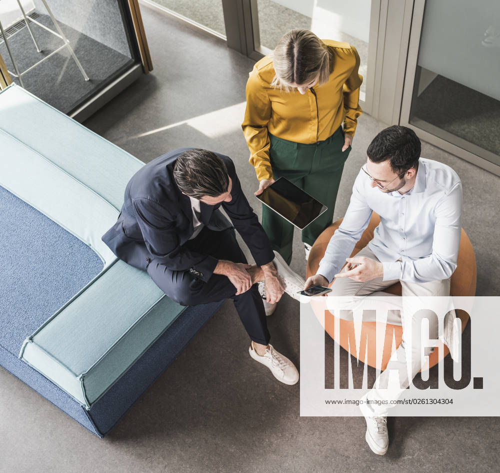 Businessman sharing smart phone with colleagues at office model released, Symbolfoto property released, UUF28622
