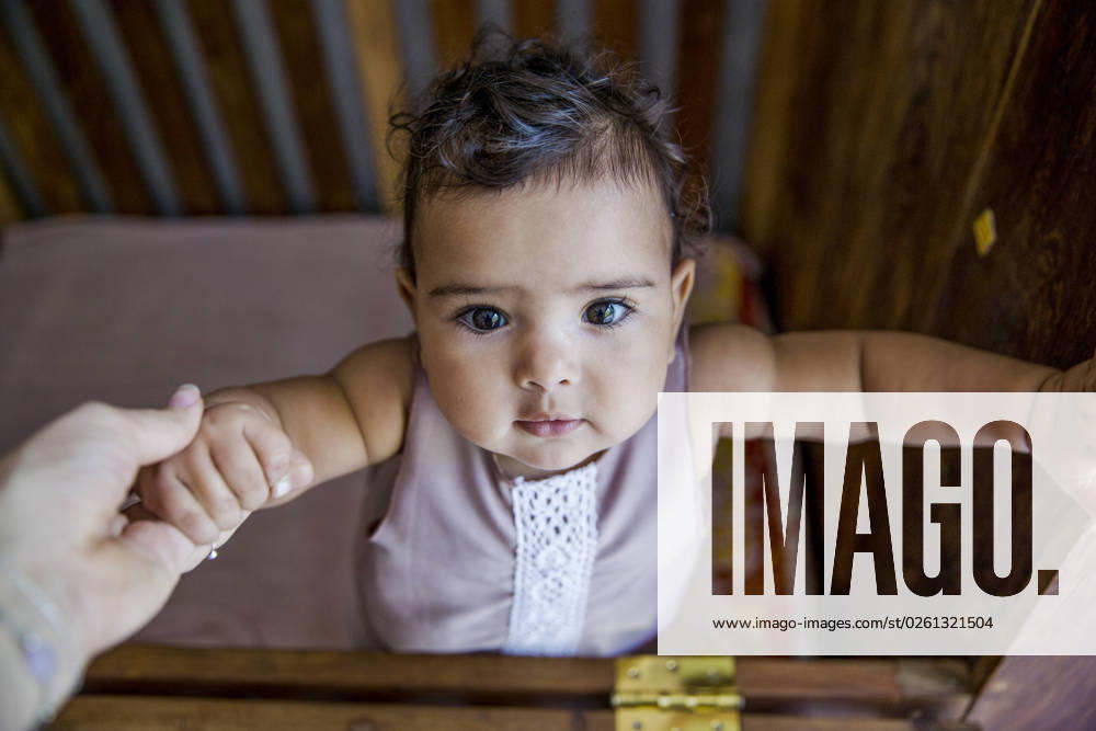 Mother holding hand of baby daughter standing in crib model released, Symbolfoto property released, IKF00817