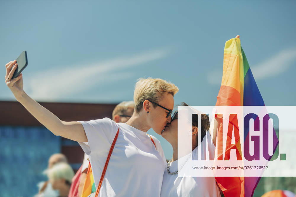Lesbian couple kissing and taking selfie with rainbow flag model released, Symbolfoto, VSNF01050