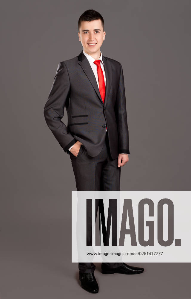 Portrait of young businessman standing on grey background