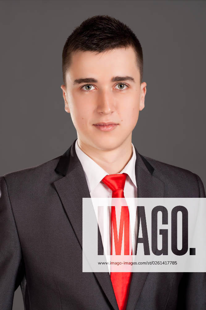Portrait of young businessman standing on grey background