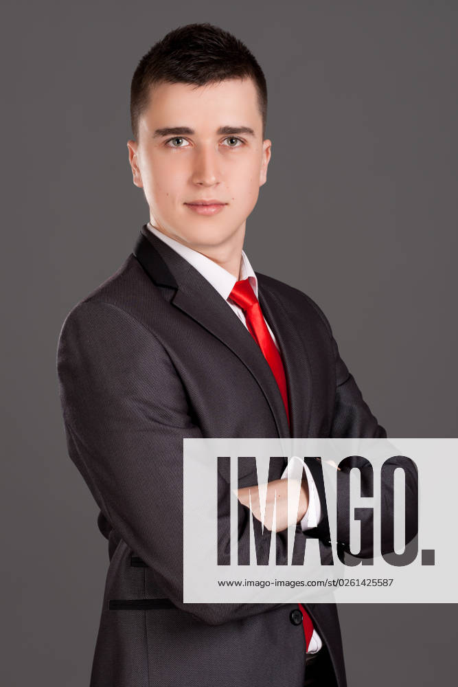 Portrait of young businessman standing on grey background