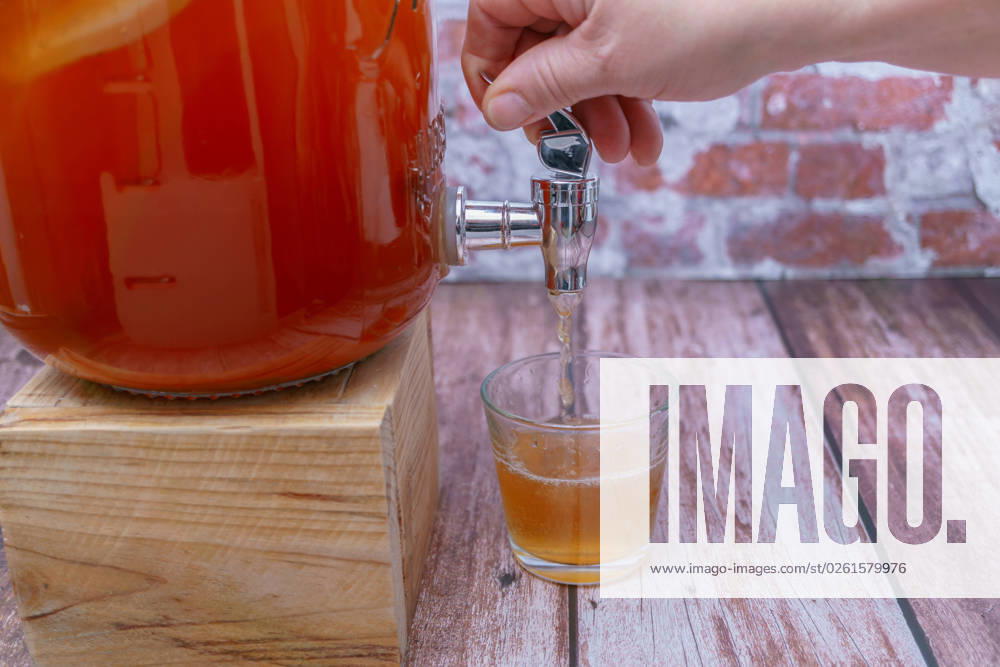 Opening the tap of a bottle of fermented kombucha tea woman s hand opening the tap of a bottle of home-made fermented kombucha tea