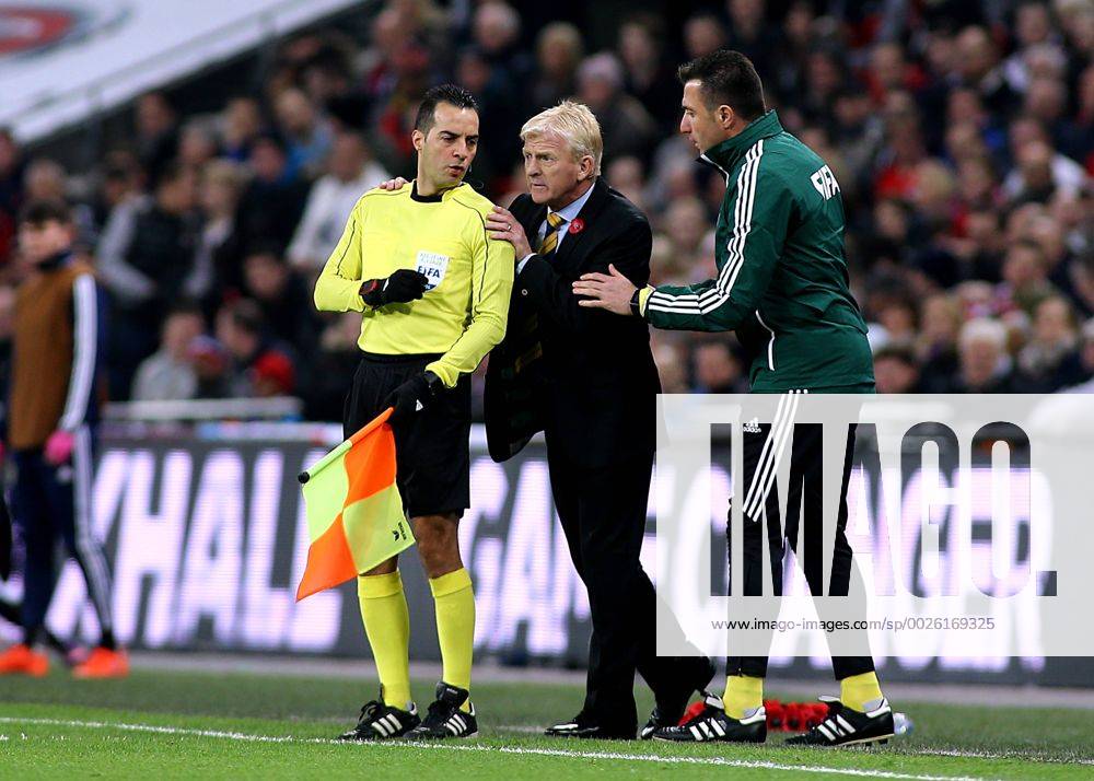 Wembley Stadium, London, England. World Cup Qualifying Football. England versus Scotland. Scotland Manager Gordon Strachan is asked by Fourth Official H& xfc;seyin G& xf6;& xe7;ek to refrain from touching Assistant referee Bahattin Duran during a discussion Kertonx ActionPlus11808491