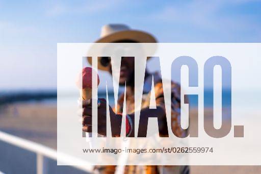 A shallow focus of a young handsome black man eating an ice cream cone at the beach *** einer seicht Fokus des einer Jung gutaussehenden Schwarz Mann essender An&Verkauf Eis Creme Kegel im der Strand 19751172 ,model released, Symbolfoto RECORD DATE NOT STATED
