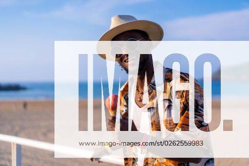 A shallow focus of a young handsome black man eating an ice cream cone at the beach *** einer seicht Fokus des einer Jung gutaussehenden Schwarz Mann essender An&Verkauf Eis Creme Kegel im der Strand 19751184 ,model released, Symbolfoto RECORD DATE NOT STATED