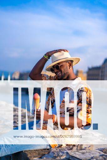 A shallow focus of a young handsome black man eating an ice cream cone at the beach *** einer seicht Fokus des einer Jung gutaussehenden Schwarz Mann essender An&Verkauf Eis Creme Kegel im der Strand 19751188 ,model released, Symbolfoto RECORD DATE NOT STATED