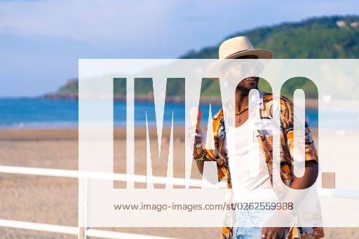 A shallow focus of a young handsome black man eating an ice cream cone at the beach *** einer seicht Fokus des einer Jung gutaussehenden Schwarz Mann essender An&Verkauf Eis Creme Kegel im der Strand 19751194 ,model released, Symbolfoto RECORD DATE NOT STATED