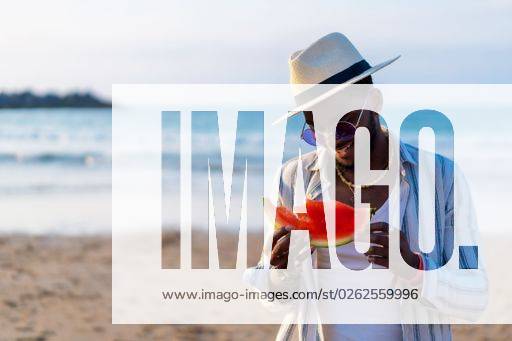 A shallow focus of a young handsome black man eating fresh watermelon at the beach *** einer seicht Fokus des einer Jung gutaussehenden Schwarz Mann essender Frisch Wassermelone im der Strand 19751276 ,model released, Symbolfoto RECORD DATE NOT STATED