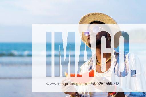 A shallow focus of a young handsome black man eating fresh watermelon at the beach *** einer seicht Fokus des einer Jung gutaussehenden Schwarz Mann essender Frisch Wassermelone im der Strand 19751278 ,model released, Symbolfoto RECORD DATE NOT STATED