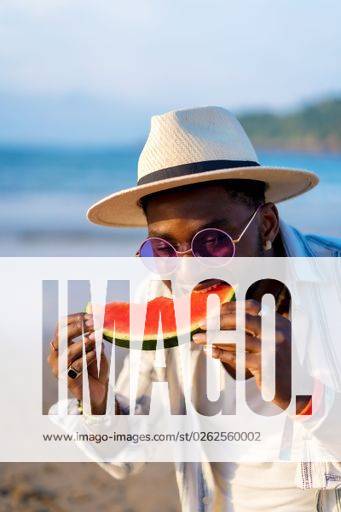 A shallow focus of a young handsome black man eating fresh watermelon at the beach *** einer seicht Fokus des einer Jung gutaussehenden Schwarz Mann essender Frisch Wassermelone im der Strand 19751284 ,model released, Symbolfoto RECORD DATE NOT STATED