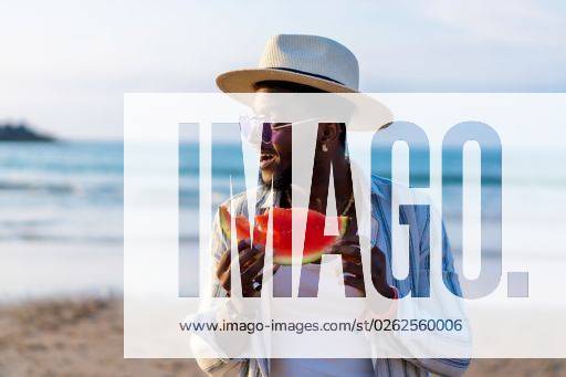 A shallow focus of a young handsome black man eating fresh watermelon at the beach *** einer seicht Fokus des einer Jung gutaussehenden Schwarz Mann essender Frisch Wassermelone im der Strand 19751289 ,model released, Symbolfoto RECORD DATE NOT STATED