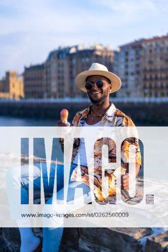 A shallow focus of a young handsome black man eating an ice cream cone at the beach *** einer seicht Fokus des einer Jung gutaussehenden Schwarz Mann essender An&Verkauf Eis Creme Kegel im der Strand 19751291 ,model released, Symbolfoto RECORD DATE NOT STATED