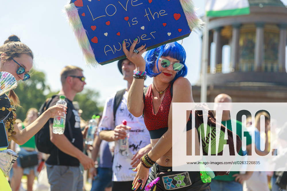 Rave the Planet 2023 Germany, Berlin on 08 July 2023 about 200 000 ravers and techno fans parade through the Tiergarten on the Starsse des 17 Juni on a hot summer day A young woman holds up a homemade sign that reads Love is the Answer