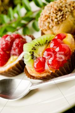 Photo of delicious dessert plate with italian fruits pastries cakes, pastry, cake, candy, dessert, black currant, kiwi, raspberries, cream puffs, stuffed, sugar, cannoli, chocolate, candies, catering, spoon, kitchen, fruit, italian, italian, tasty, gourmet, pies, cream, candle, leaves, decoration, fire, table, food, restaurant