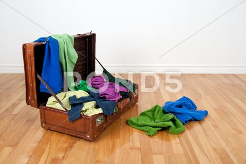 Leather suitcase on a wooden floor in an empty room, full of colorful clothing. apparel, bag, baggage, blue, brown, classic, clothes, clothing, colorful, colour, colourful, excess, fabric, fashion, floor, full, garment, green, hardwood, holiday, journey, leather, luggage, material, messy, multicolored, nobody, old, old fashioned, old-fashioned, open, overfilled, packed, parquet, retro, room, suitcase, textile, too much, tourism, travel, trip, vacation, vintage, wall, wear, white, wooden