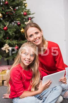 Smiling mother and daughter using digital tablet at christmas tree with gift boxes beautiful,celebration,festive,greeting,happy,holiday,xmas,smiling,adult,people,happiness,child,family,connection,childhood,kid,presents,adorable,cozy,home,communication,wireless,gifts,together,togetherness,indoors,using,daughter,mother,parent,gadget,mom,christmastime,relationship,mummy,youngster,parenthood,preteen,girlhood,christmas tree,caucasian girl,new year,merry christmas,christmas eve,gift boxes,digital tablet,caucasian woman,digital device