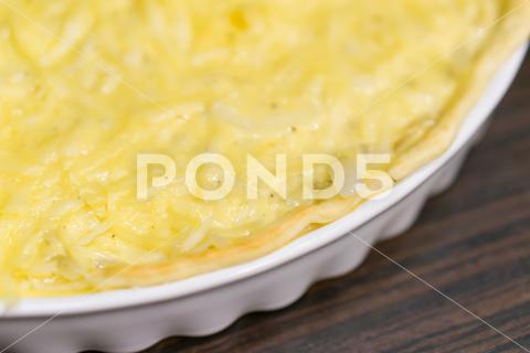 A soft focus shot of an onion tart in a white dish on a wooden table food, tart, onion, meal, baked, pie, cheese, snack, vegetable, pastry, homemade, lunch, dinner, quiche, dish, crust, cooking, healthy, french, cuisine, vegetarian, gourmet, cream, tasty, delicious, table, plate, breakfast, wooden, white