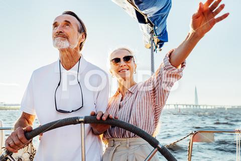 Mature couple standing at steering wheel on their yacht and enjoying vacation mature, couple, standing, steering wheel, yacht, vacation, journey, looking, sailboat, smiling, partner, holiday, happy, people, caucasian, adventure, lifestyle, woman, man, outdoors, elderly, senior, real