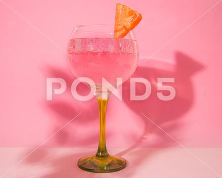 A glass of gin and tonic on a pink background drink, glass, beverage, alcohol, cocktail, cold, bar, liquid, background, juice, transparent, glasses, reflection, water, liquor, crystal, ice, light, party, refreshing, alcoholic, cool, cube, pink