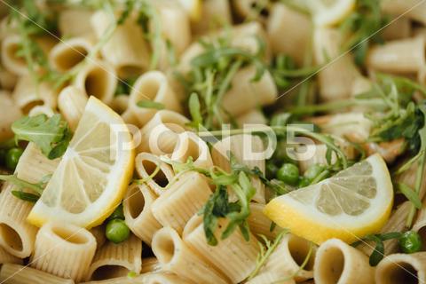 A close-up shot of rigatoni pasta with lemons and greens served on a plate. abstract, art, background, basil, bowl, cheese, colorful, concept, contemporary, creative, delicious, design, dinner, down, fashion, flat, food, frame, fresh, garlic, green, healthy, hipster, idea, ingredient, italian, lay, lemon, life, macaroni, meal, minimal, parmesan, pasta, pea, penne, pesto, plate, recipe, red, rigatoni, still, top, trend, vegetarian, view, cherry, tomatoes, vertical