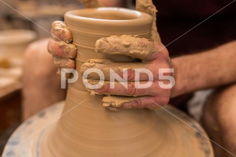 Crop unrecognizable sculptor with equipment giving shape while sculpting with brown clay on throwing wheel man, shape, clay, sculpt, equipment, process, motion, jug, ceramic, skill, male, sculptor, workshop, art, artist, handicraft, earthenware, ceramist, craft, create, dirty, form, hobby, handmade, maker, master, molding, occupation, pottery, utensil, wet, wheel, professional, work, artisan, throw, small business, talent, workplace, crop, unrecognizable, faceless, anonymous, horizontal, body part, blur, indoors