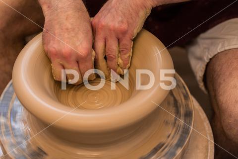 Crop unrecognizable sculptor with equipment giving shape while sculpting with brown clay on throwing wheel man, shape, clay, sculpt, equipment, process, motion, jug, ceramic, skill, male, sculptor, workshop, art, artist, handicraft, earthenware, ceramist, craft, create, dirty, form, hobby, handmade, maker, master, molding, occupation, pottery, utensil, wet, wheel, professional, work, artisan, throw, small business, talent, workplace, crop, unrecognizable, faceless, anonymous, horizontal, body part, blur, indoors, top view, from above