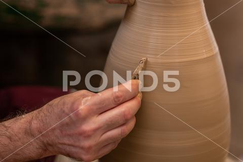 Crop unrecognizable sculptor with equipment giving shape while sculpting with brown clay on throwing wheel man, shape, clay, sculpt, equipment, process, motion, jug, ceramic, skill, male, sculptor, workshop, art, artist, handicraft, earthenware, ceramist, craft, create, dirty, form, hobby, handmade, maker, master, molding, occupation, pottery, utensil, wet, wheel, professional, work, artisan, throw, small business, talent, workplace, crop, unrecognizable, faceless, anonymous, horizontal, body part, blur, indoors