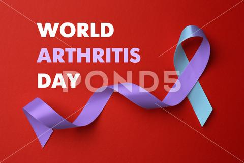 World Arthritis Day. Blue and purple awareness ribbon on red background, top view arthritis,awareness,background,blue,body,bone,care,concept,day,design,disease,flat,health,help,human,illness,inflammation,international,joint,knee,lay,medical,medicine,month,object,october,osteoporosis,pain,prevention,problem,purple,red,rheumatism,rheumatoid,ribbon,satin,sign,silk,support,symbol,top,view,violet,wad,world