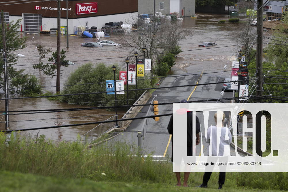 People stand on a hill surveying cars abandoned in floodwater in a mall parking lot following a major rain event in Halifax on Saturday, July 22, 2023. Halifax Canada - ZUMAc35_ 20230722_zaf_c35_031