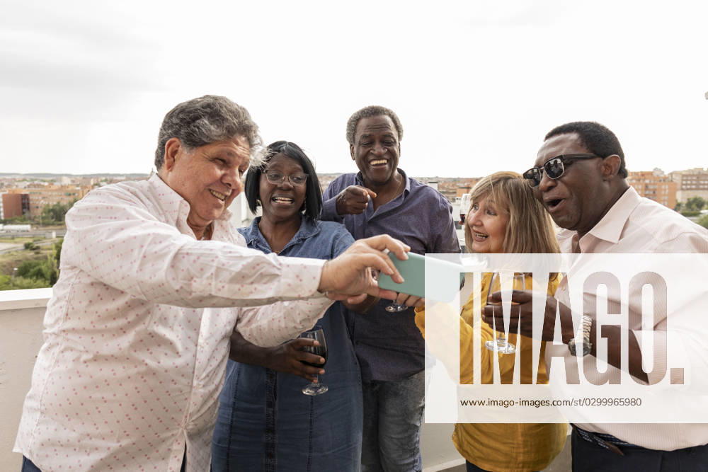 Senior man showing photo to friends at dinner party in balcony model released, Symbolfoto property released, JCCMF10655