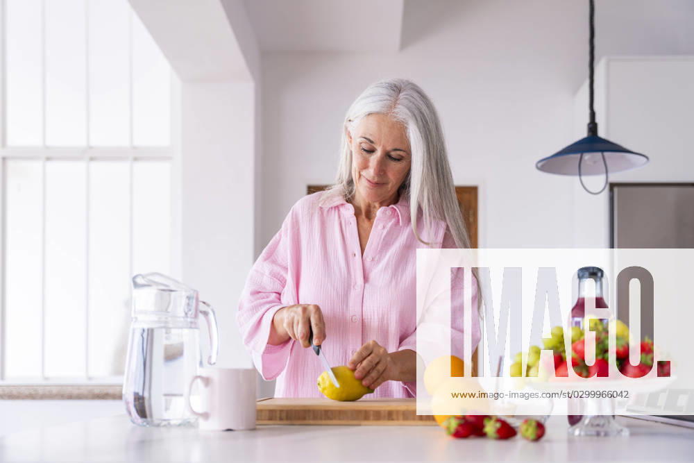 Mature woman cutting lemon in kitchen at home model released, Symbolfoto property released, OIPF03314