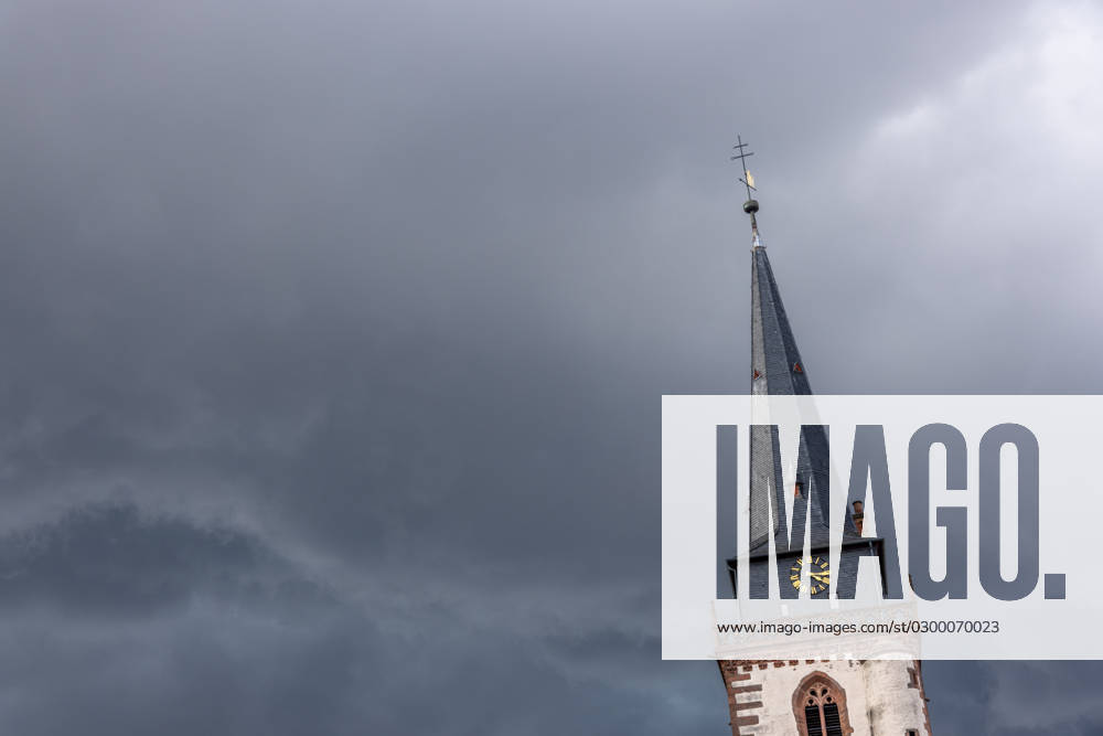 Dark clouds over the church tower Dark clouds of a thunderstorm are seen in the afternoon in the sky above the tower of the Catholic Church St Ursula , Oberursel Hesse Germany