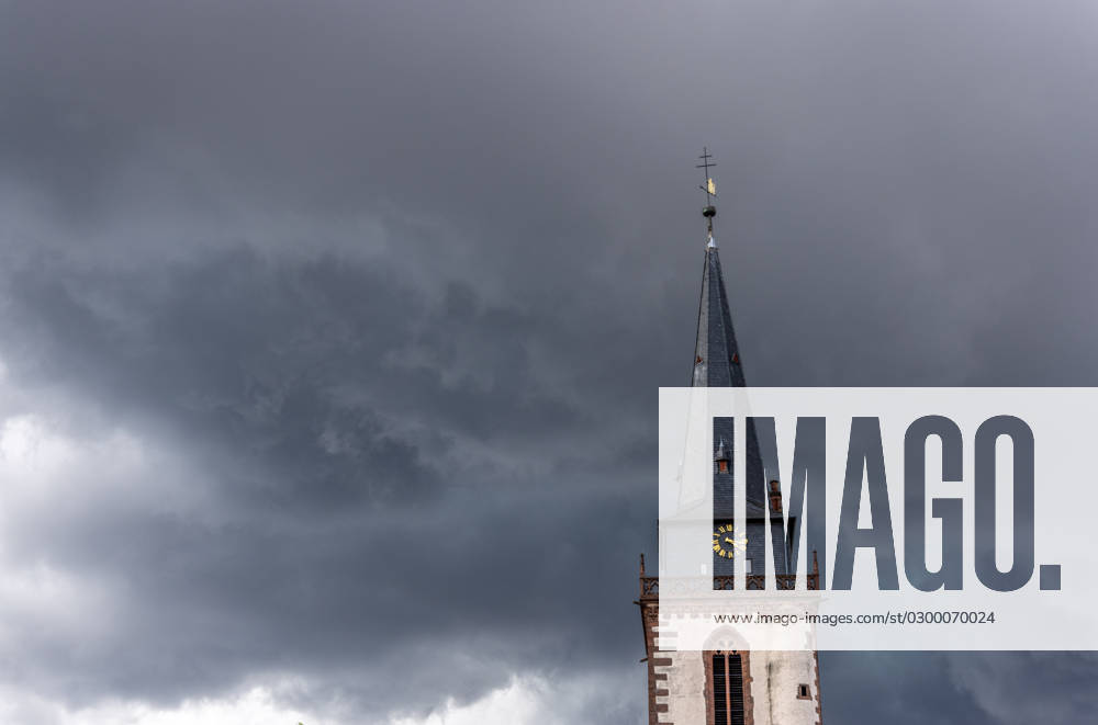 Dark clouds over the church tower Dark clouds of a thunderstorm are seen in the afternoon in the sky above the tower of the Catholic Church St Ursula , Oberursel Hesse Germany