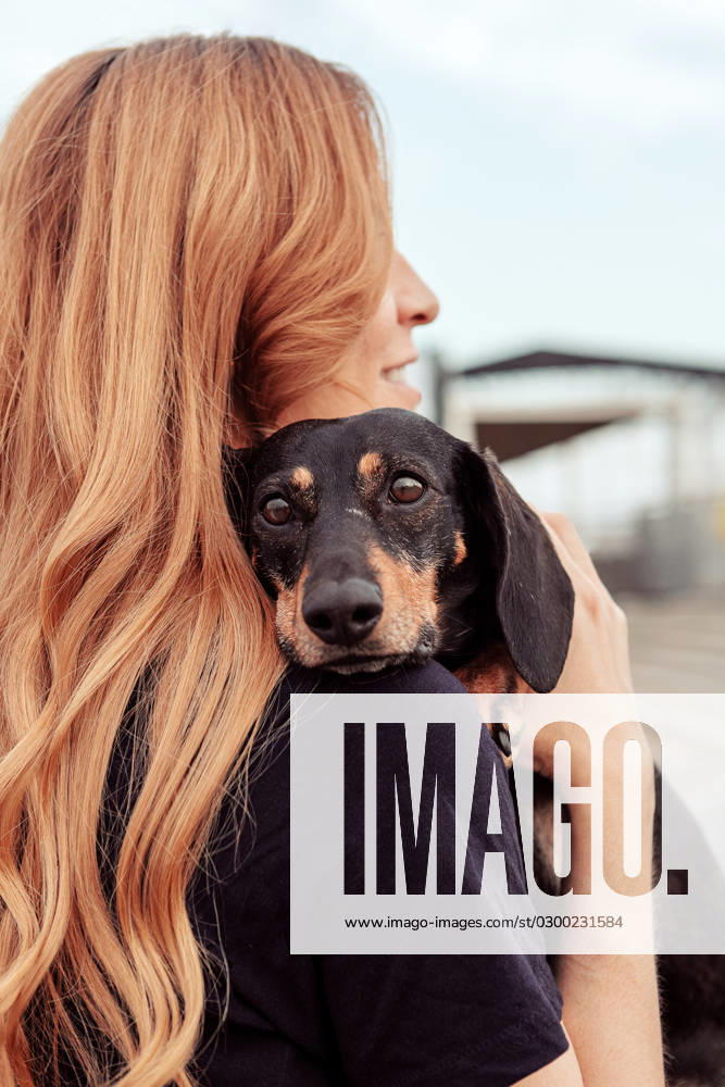 MR_ID15063_14408_LaraVacas.jpg Side view of redhead woman embracing Dachshund dog while walking on street together during weekend MR AlfonsoSaenz_ID15063_459454_005