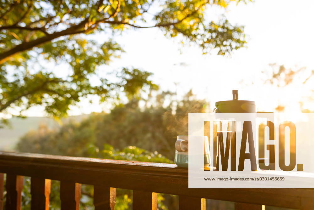 Balcony of log cabin with coffee press and coffee mug on sunny day. Nature, agriculture, summer, tranquillity and drink.