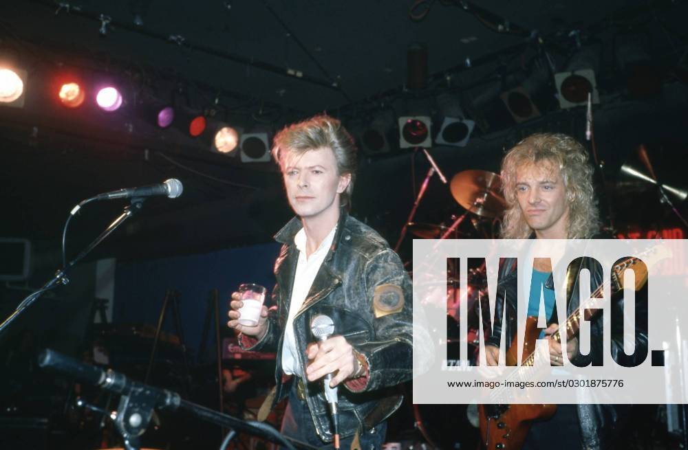 David Bowie performing on stage with drink in hand, wearing a black leather jacket, with Peter Frampton on guitar, New york, 1980s. Photo: Oscar Abolafia Everett Collection (davidbowie010)OSAB001 J4861 PUBLICATIONXNOTxINxCANxCHNxFRAxITAxJPNxNORxPOLxRUSxESPxUKxUSA