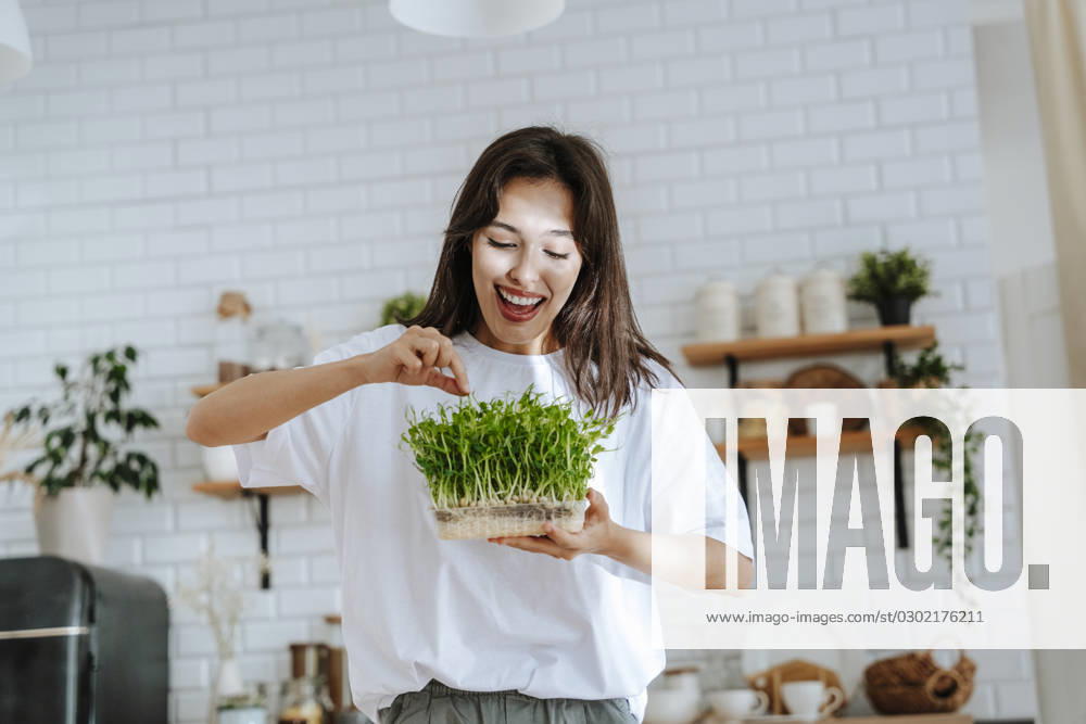 Smiling young woman holding homegrown herbs in kitchen model released, Symbolfoto property released, NLAF00073