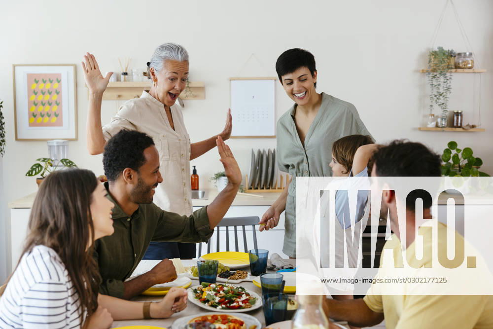 Smiling family giving high-five on dining table in kitchen model released, Symbolfoto property released, EBSF03688