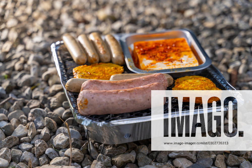 Bavaria, Germany - 2 September 2023: Vegetarian Grilling, Bratwurst Vegan and Vegetarian on a disposable grill on pebbles next to a meadow. Meat and sausage substitutes
