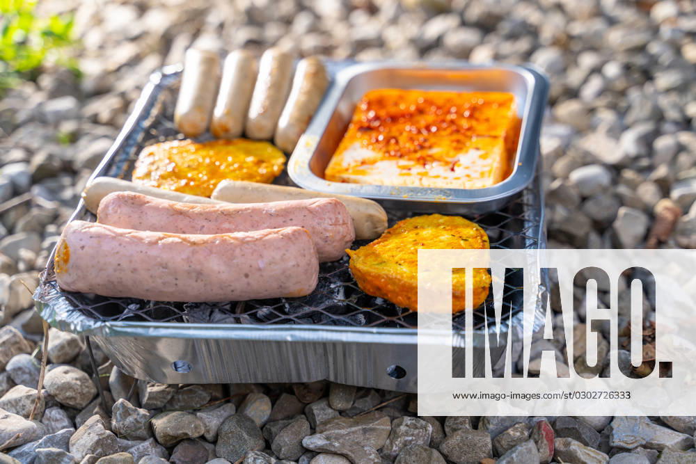 Bavaria, Germany - 2 September 2023: Vegetarian Grilling, Bratwurst Vegan and Vegetarian on a disposable grill on pebbles next to a meadow. Meat and sausage substitutes
