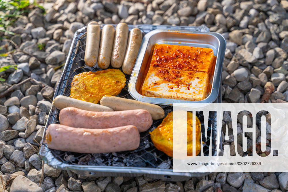 Bavaria, Germany - 2 September 2023: Vegetarian Grilling, Bratwurst Vegan and Vegetarian on a disposable grill on pebbles next to a meadow. Meat and sausage substitutes