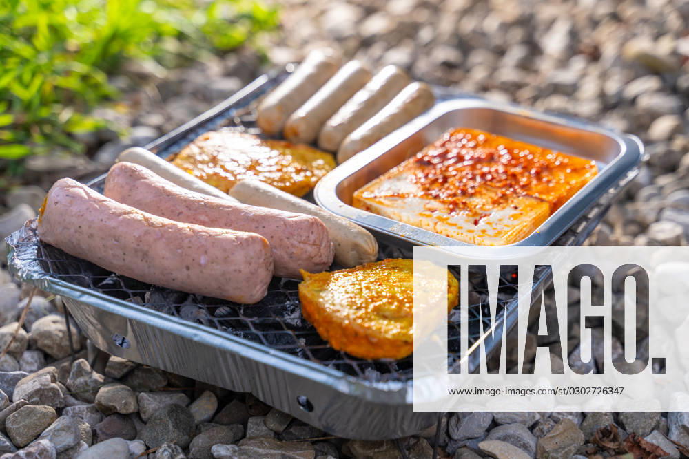 Bavaria, Germany - 2 September 2023: Vegetarian Grilling, Bratwurst Vegan and Vegetarian on a disposable grill on pebbles next to a meadow. Meat and sausage substitutes